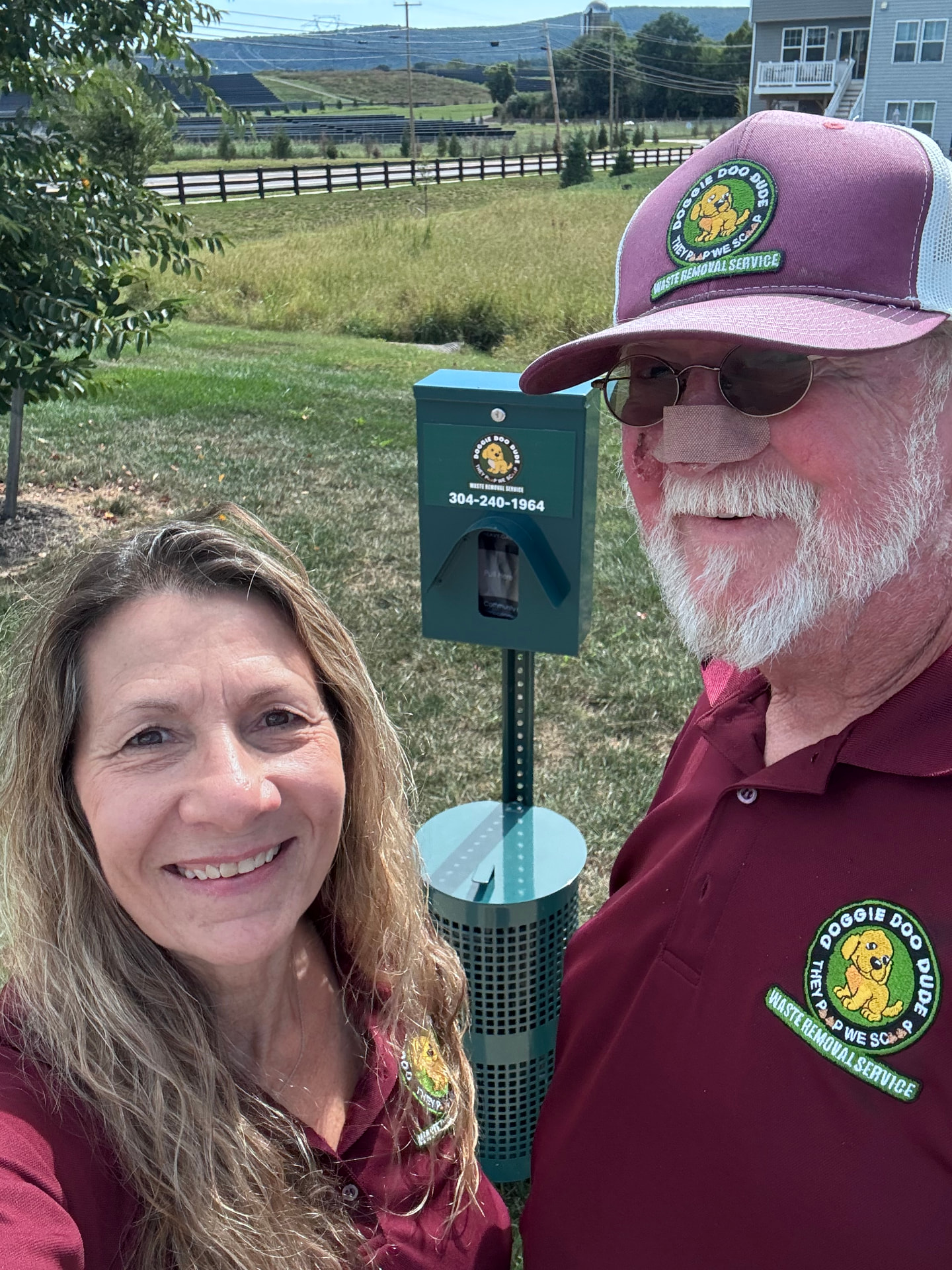 The founders of Doggie Doo Dude in front of a pet waste station in a WV community